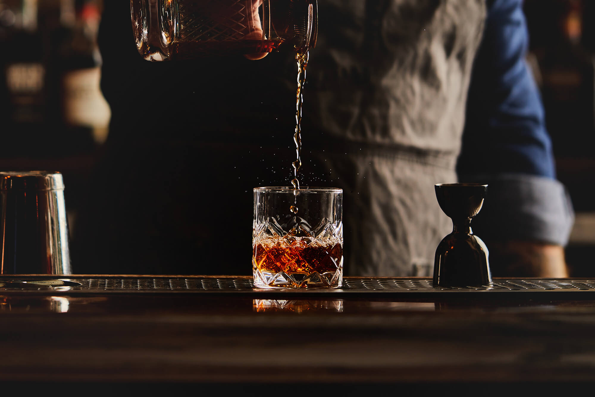 Bartender pouring whiskey into a glass.